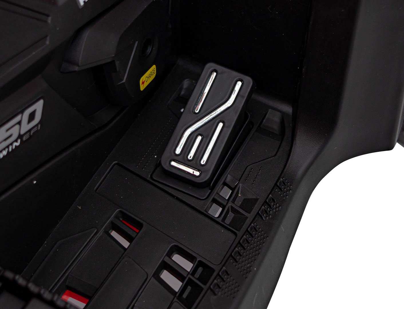Close-up of black Can Am Outlander ATV foot pedal with textured grip and red safety details