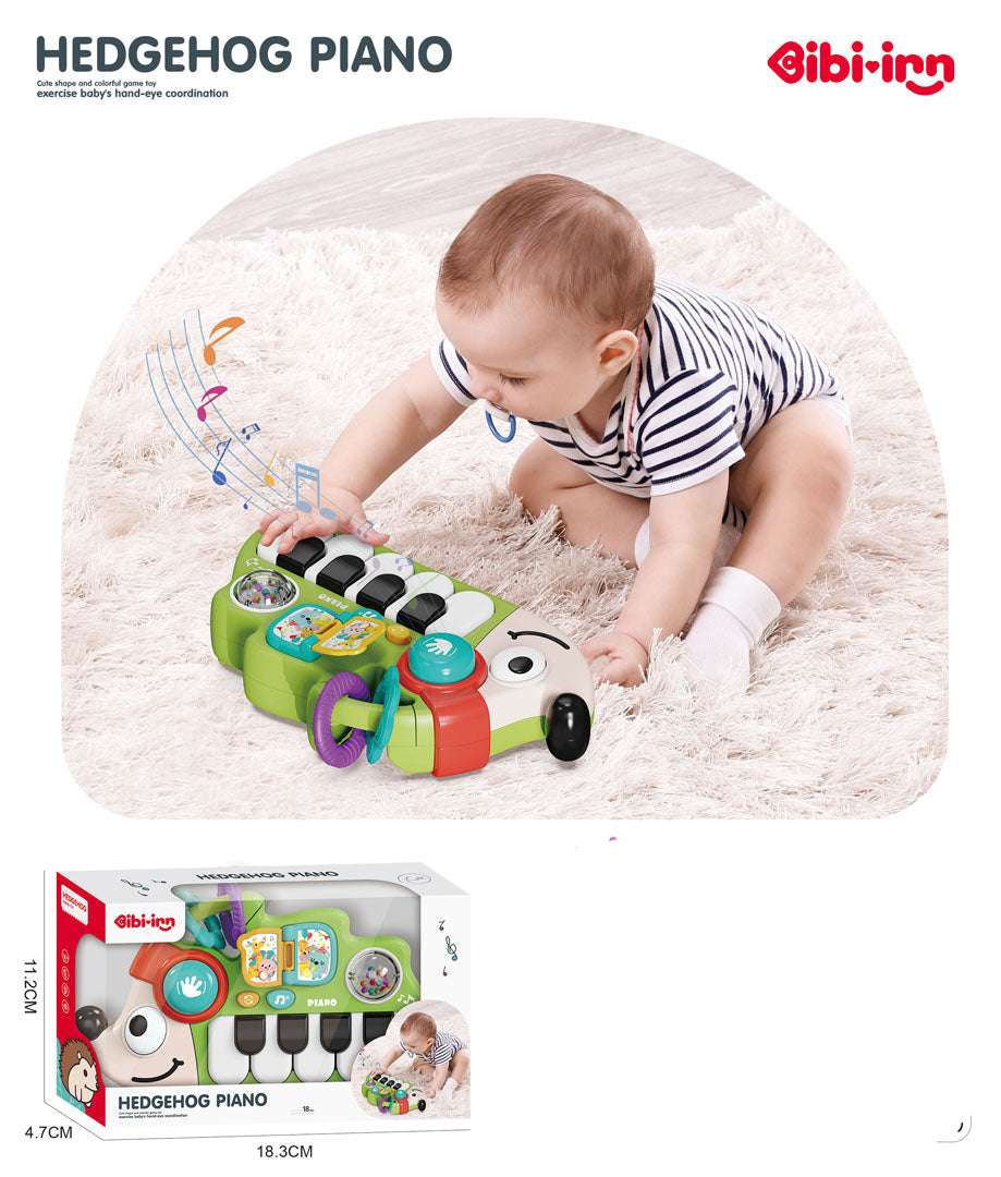 Baby playing with green Pianinko Jeżyk musical toy piano on soft carpet