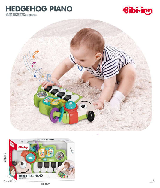 Baby playing with green Pianinko Jeżyk musical toy piano on soft carpet